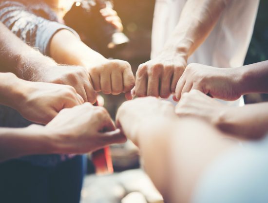 Close up of young people putting their hands together. Team with stack of hands showing unity and teamwork.